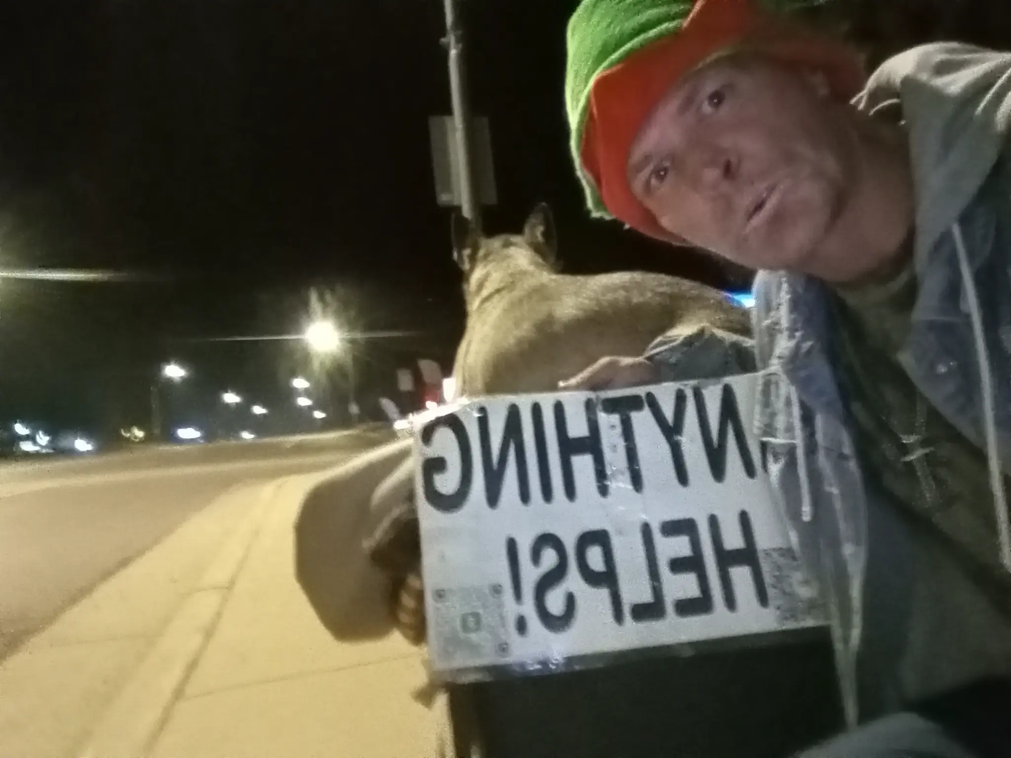 Matthew and Cleopatra on the streets at night with 'Anything Helps' sign
